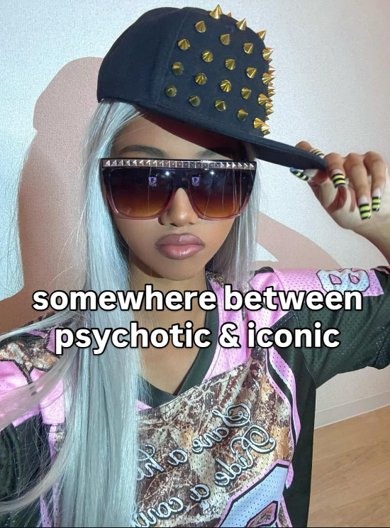 Person wearing a black cap with gold studs, sunglasses, and a patterned shirt with text.