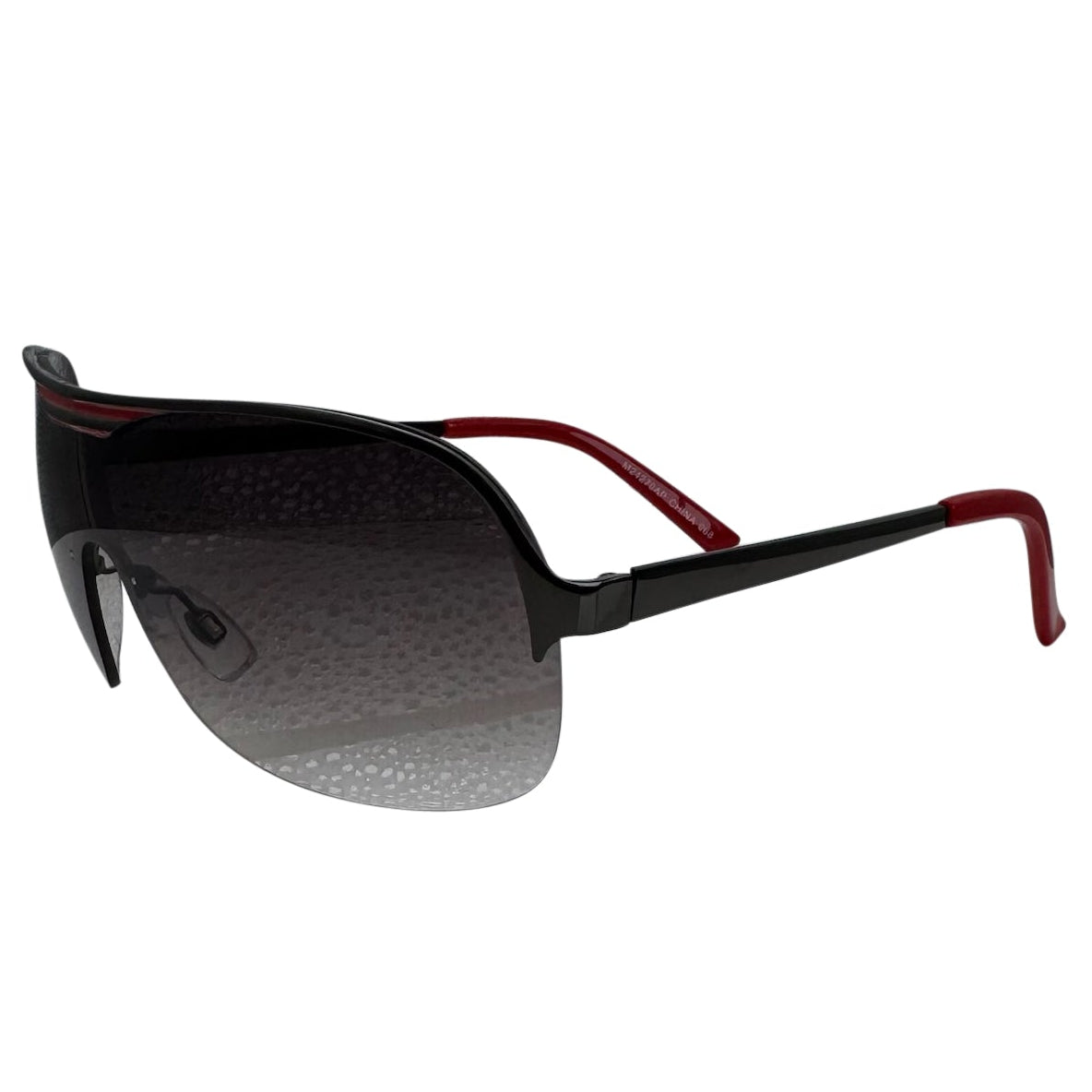 A side-facing product shot of the EXOTIC sunglasses, featuring a rimless shield design with oversized, dark-to-light gradient lenses. The frames are accented by a sleek black/ red double-bridge bar across the top and white arms visible through the lenses.