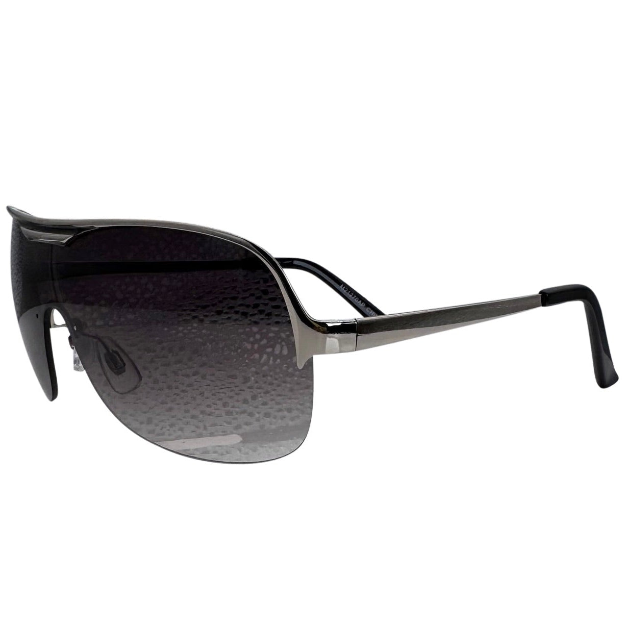 A front-facing product shot of the EXOTIC sunglasses, featuring a rimless shield design with oversized, dark-to-light gradient lenses. The frames are accented by a sleek silver double-bridge bar across the top and silver arms visible through the lenses.