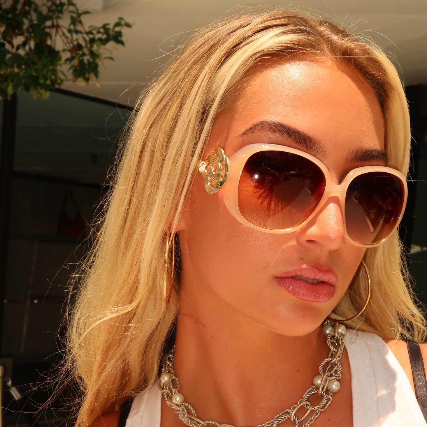 Woman wearing sunglasses and a white top with a blurred background