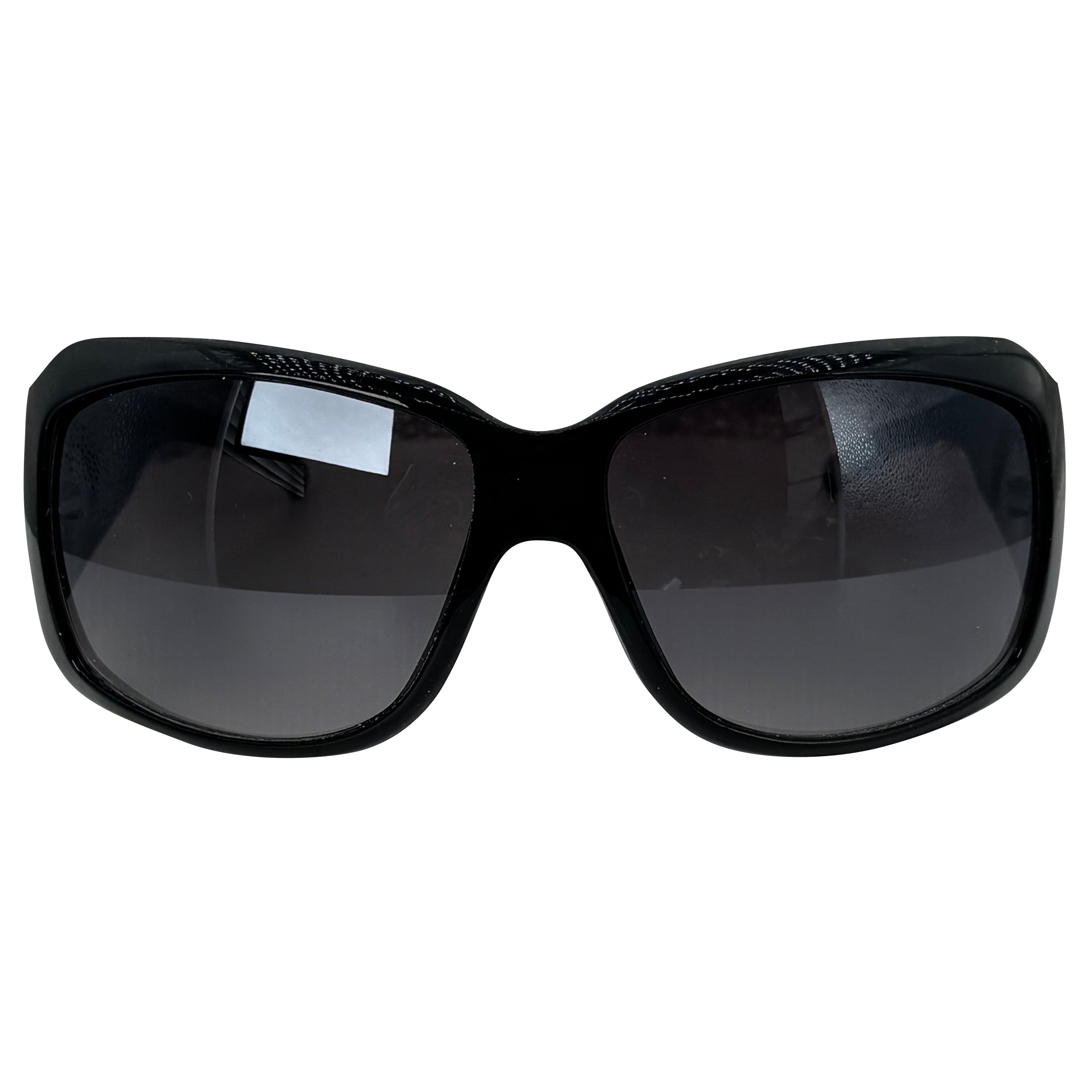 Black oversized sunglasses with dark tinted lenses and a glossy frame, shown against a plain white background.