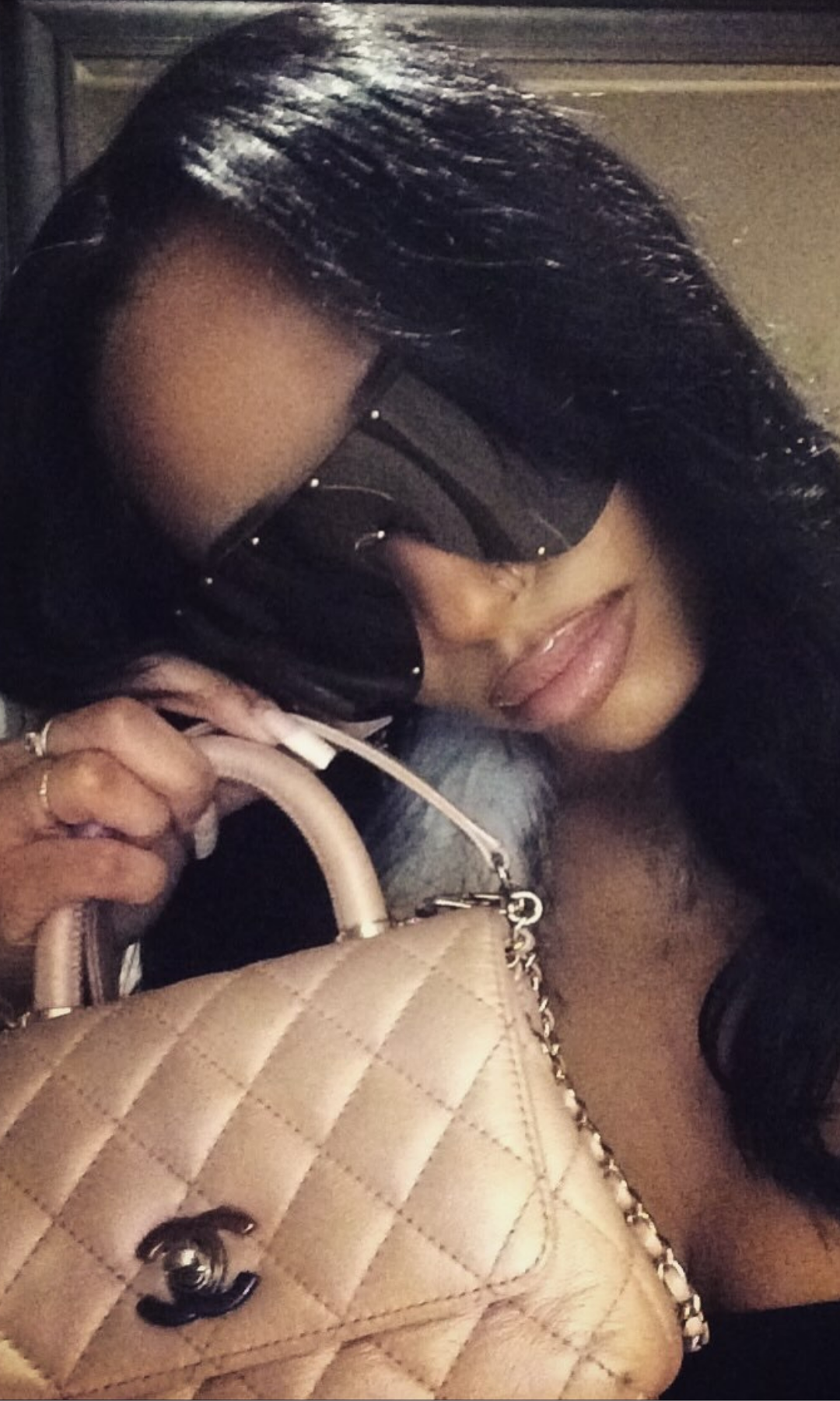 Woman holding a Chanel handbag with sunglasses on, blurred background