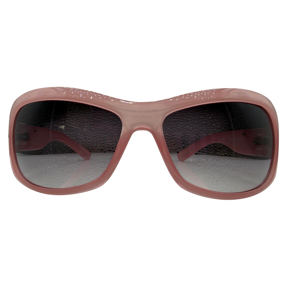 A pair of NICOLE sunglasses with a translucent dusty rose pink frame and dark gray lenses, shown against a plain white background.