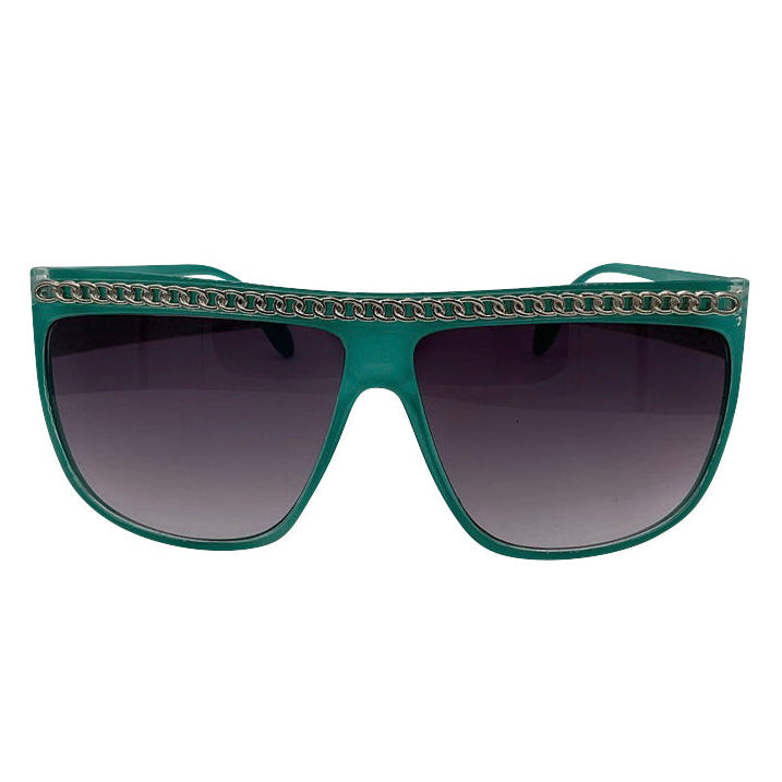 Front view of SCANDAL sunglasses featuring a vibrant teal-green flat-top frame with a silver chain-link inlay across the brow and dark gradient lenses.