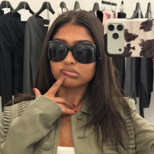 Person wearing sunglasses and a green jacket in a clothing store