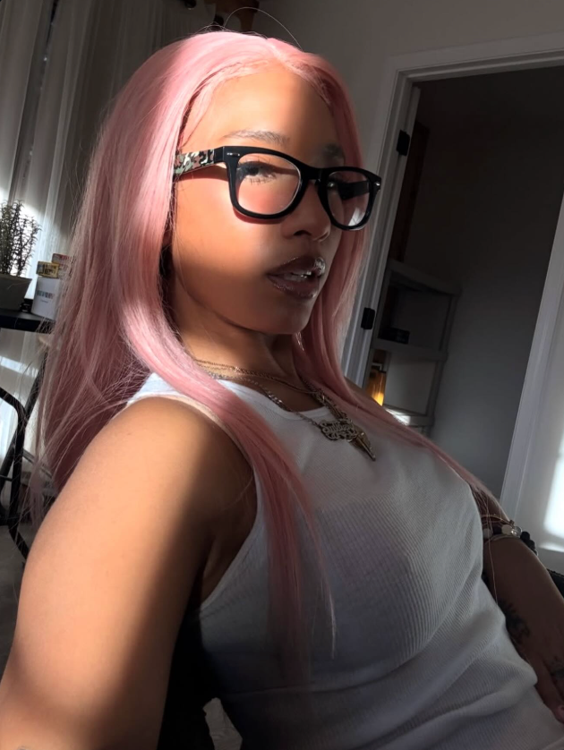 Person with pink hair and glasses in a casual setting