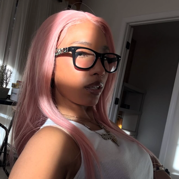 Person with pink hair and glasses in a casual setting