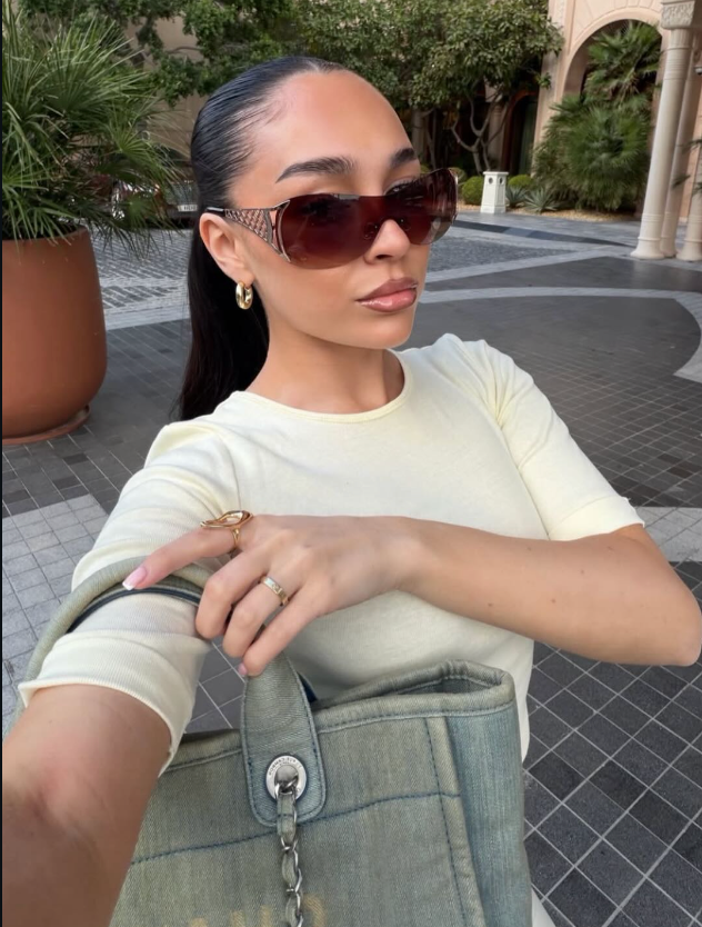 Woman wearing sunglasses and a light-colored top outdoors