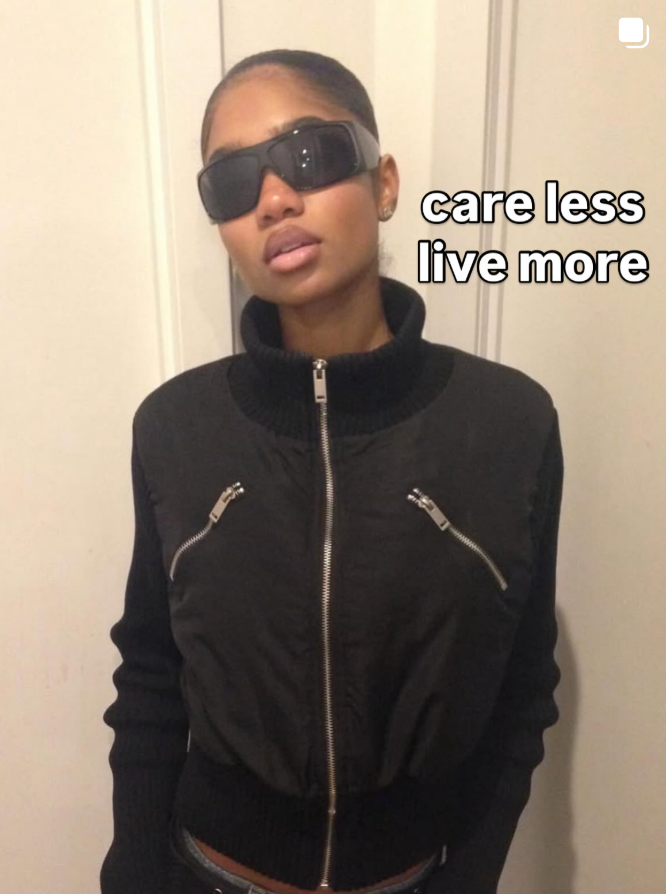 Person wearing a black jacket with sunglasses and text 'care less live more' on a plain background