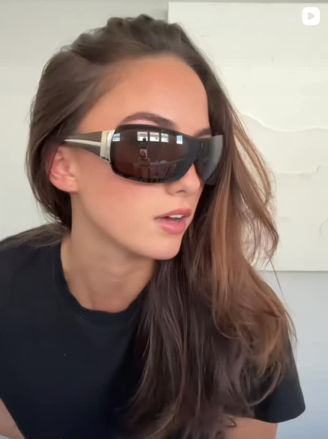 Woman wearing futuristic sunglasses with a plain background
