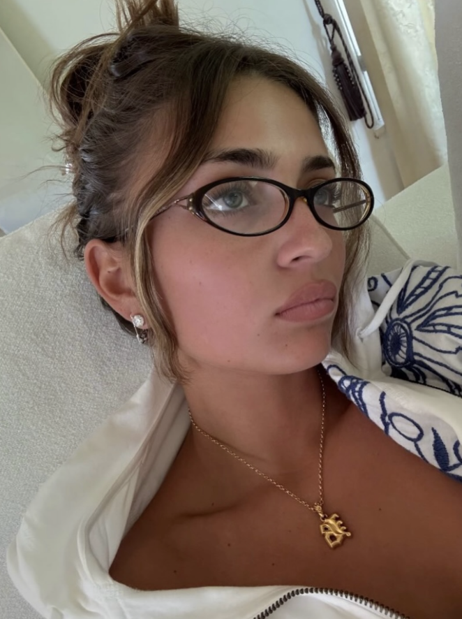 Woman wearing glasses with a neutral expression, indoors.